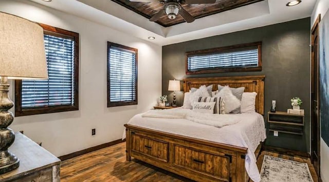 bedroom featuring a tray ceiling, ceiling fan, and dark hardwood / wood-style floors