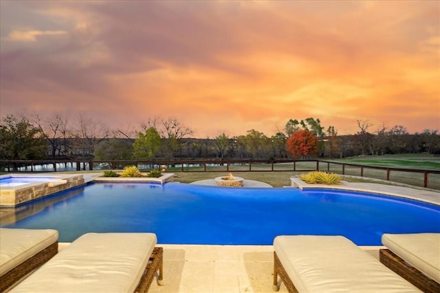 pool at dusk with an in ground hot tub