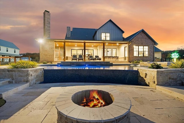 back house at dusk featuring a patio and a fire pit