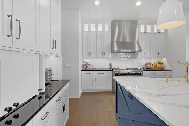 kitchen featuring white cabinetry, sink, light stone countertops, and wall chimney exhaust hood