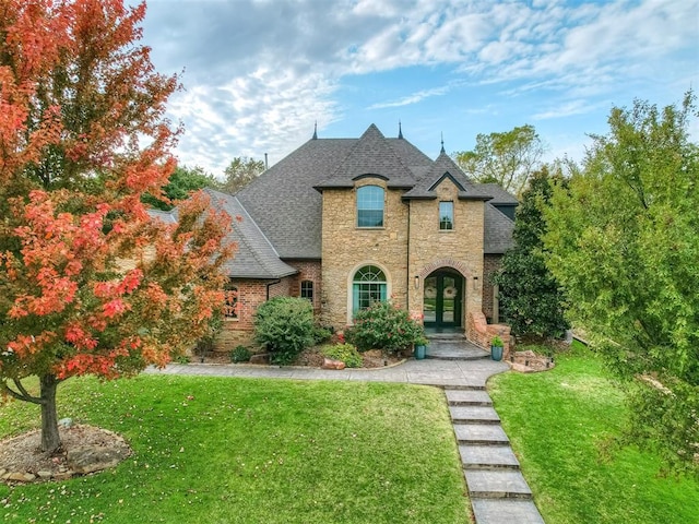 french country inspired facade featuring french doors and a front yard