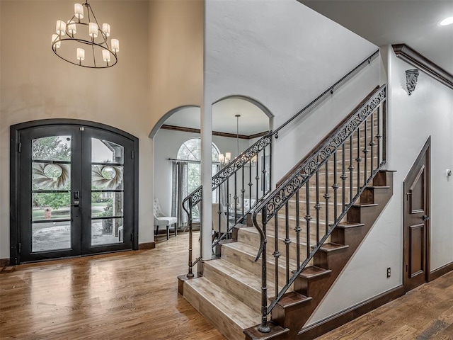 foyer entrance featuring french doors, a chandelier, plenty of natural light, and hardwood / wood-style flooring