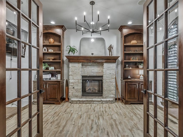 living room with a fireplace, light hardwood / wood-style floors, french doors, and an inviting chandelier