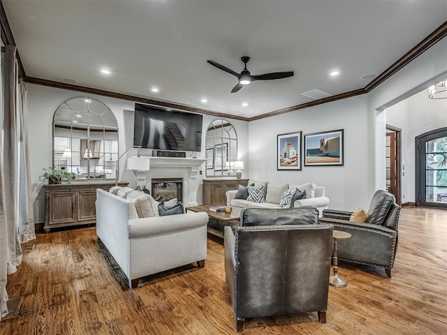 living room with crown molding, ceiling fan, and wood-type flooring