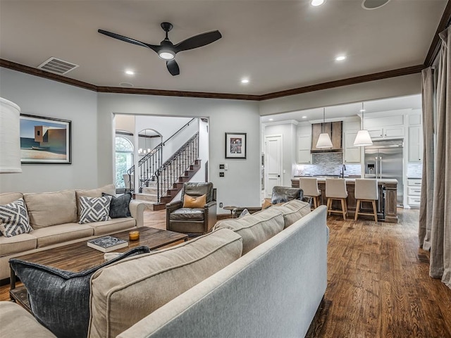 living room with crown molding, ceiling fan with notable chandelier, and dark hardwood / wood-style floors