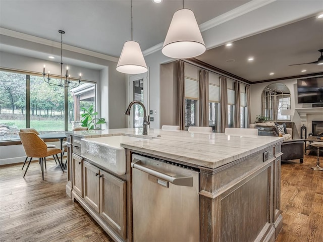 kitchen featuring wood-type flooring, pendant lighting, stainless steel dishwasher, and an island with sink