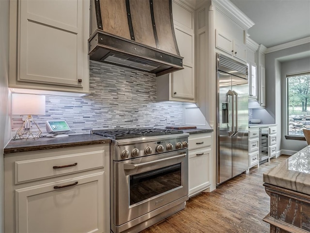 kitchen featuring decorative backsplash, light wood-type flooring, custom exhaust hood, crown molding, and high quality appliances