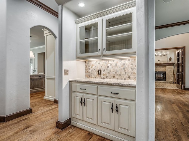 bar with white cabinetry, crown molding, and light hardwood / wood-style flooring