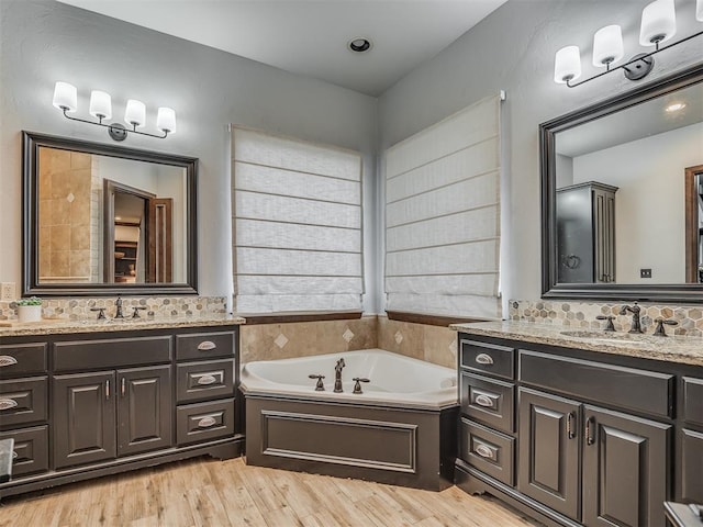 bathroom with hardwood / wood-style floors, vanity, a tub, and tasteful backsplash