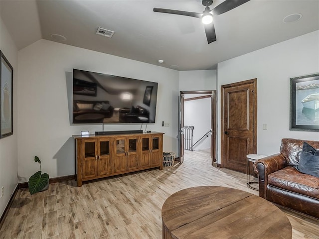 living room with ceiling fan, light hardwood / wood-style floors, and vaulted ceiling