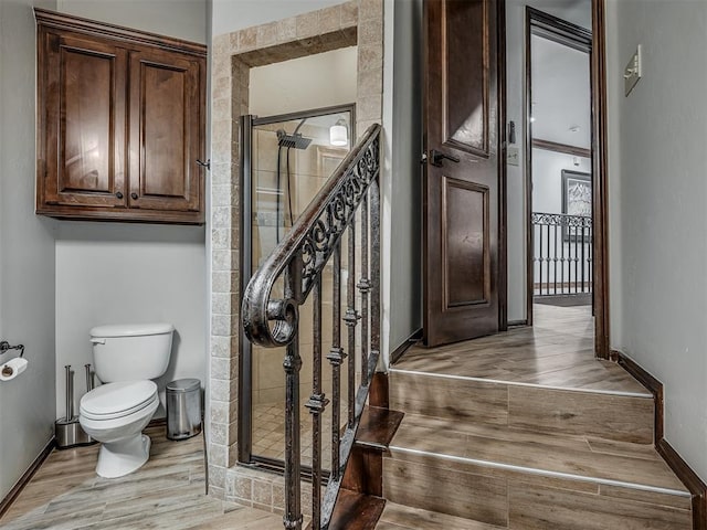 interior space featuring wood-type flooring, toilet, and a shower with shower door