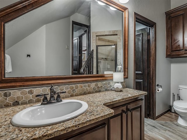 bathroom with vanity, hardwood / wood-style flooring, toilet, tasteful backsplash, and an enclosed shower