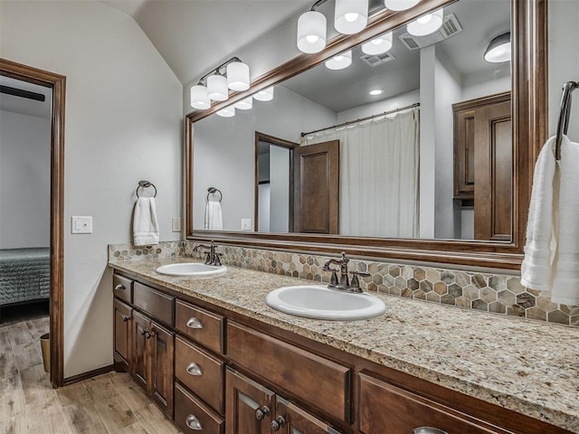 bathroom featuring decorative backsplash, vanity, wood-type flooring, and lofted ceiling