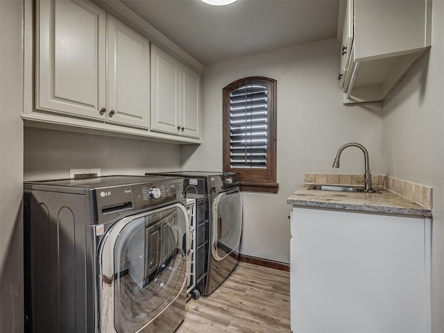 laundry area featuring cabinets, independent washer and dryer, light hardwood / wood-style flooring, and sink