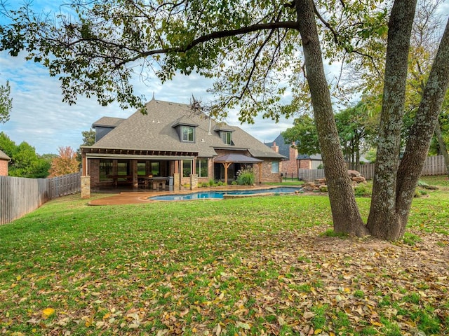 rear view of property featuring a patio, a fenced in pool, and a lawn