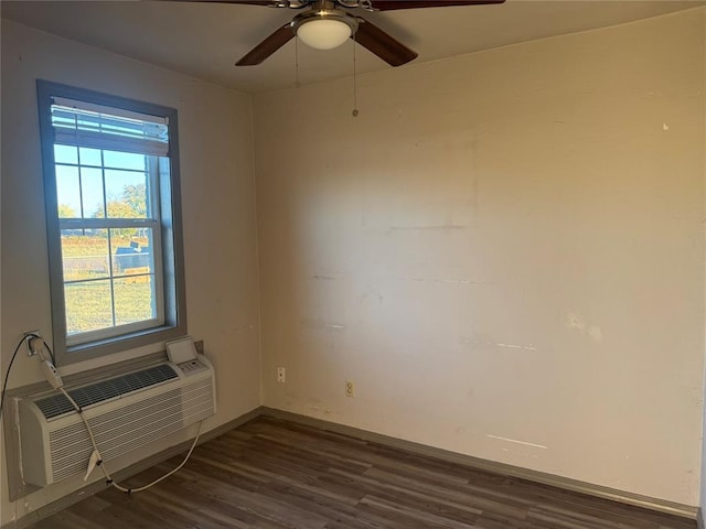 701 N Park Ln, Altus, OK 73521 - unfurnished room with dark wood-style floors, baseboards, a ceiling fan, and a wall mounted air conditioner