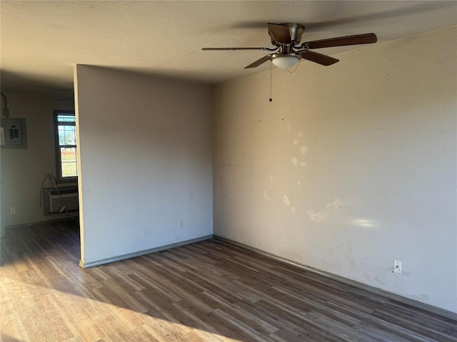 empty room with electric panel, ceiling fan, a wall mounted air conditioner, and dark hardwood / wood-style floors