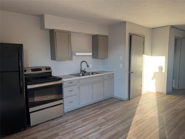 kitchen with gray cabinetry, electric range, sink, light hardwood / wood-style floors, and black refrigerator