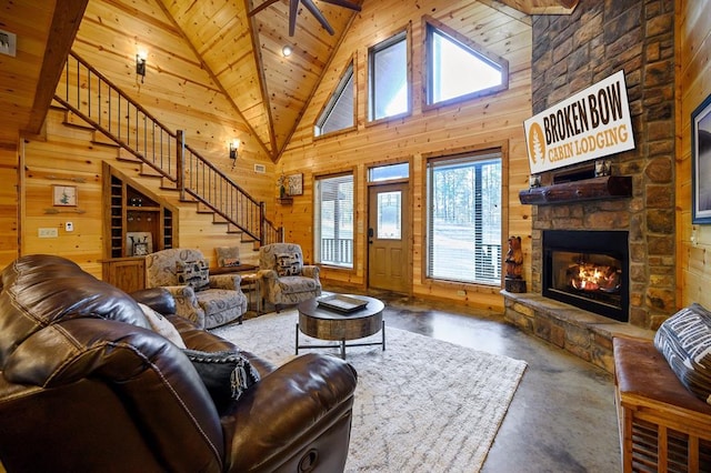 living room with wood walls, wooden ceiling, high vaulted ceiling, a stone fireplace, and concrete flooring