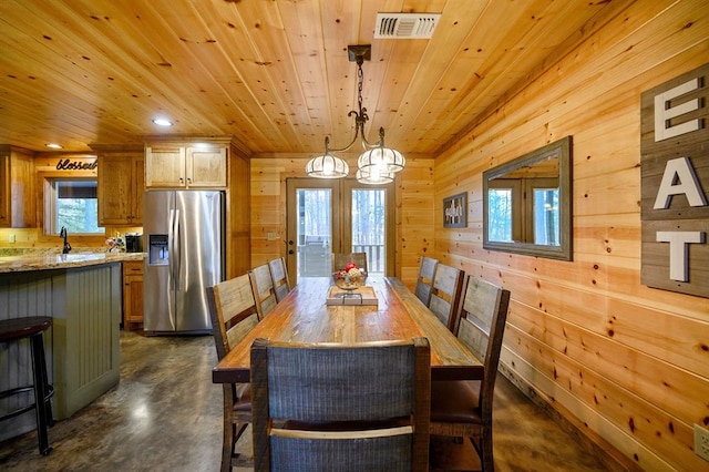 dining room with a chandelier, wooden walls, wooden ceiling, and sink