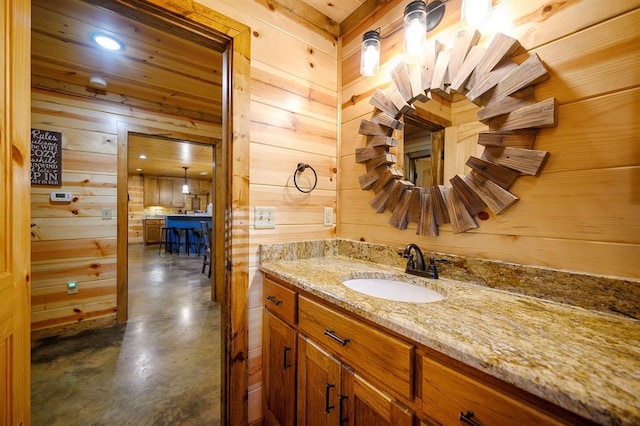 bathroom with wooden walls, vanity, and concrete flooring