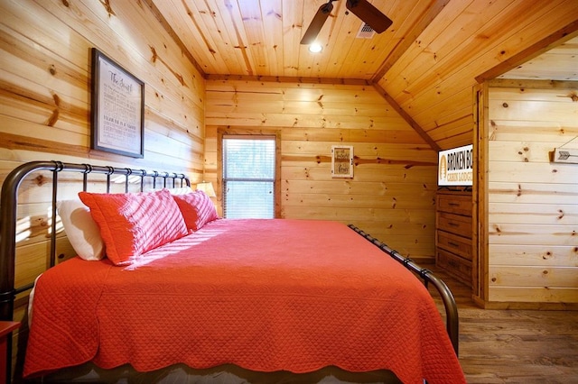 bedroom with ceiling fan, wood-type flooring, wooden walls, and vaulted ceiling