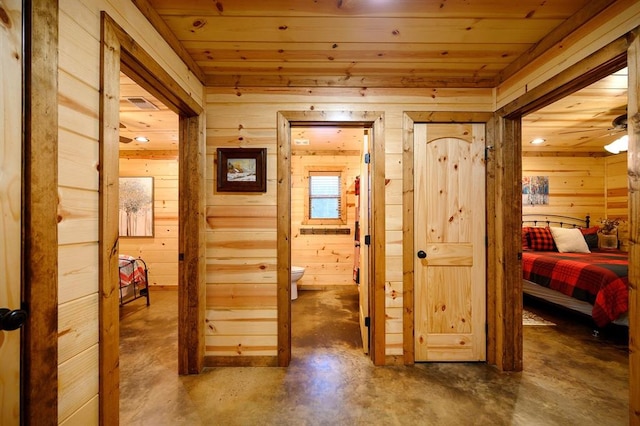 corridor featuring wood ceiling, wood walls, and concrete floors