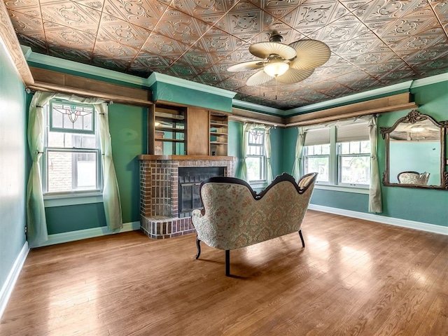 living area with hardwood / wood-style floors, a brick fireplace, a wealth of natural light, and ceiling fan