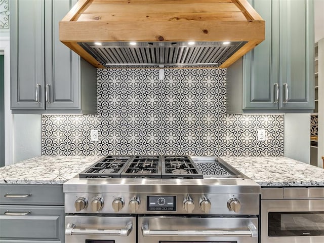 kitchen with light stone countertops, decorative backsplash, ventilation hood, and stainless steel appliances