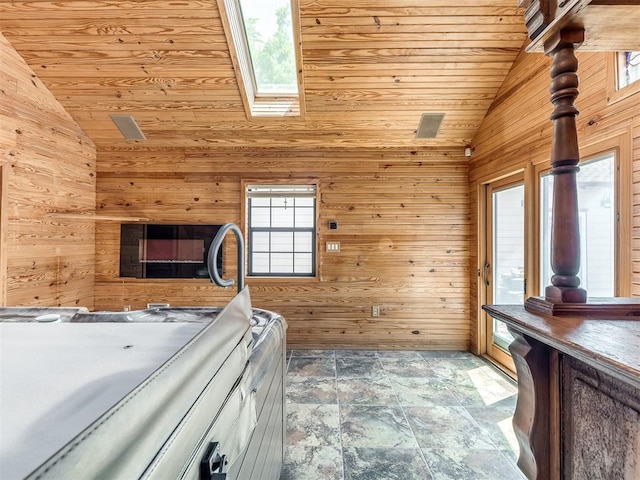 unfurnished bedroom with wooden ceiling, a skylight, high vaulted ceiling, and wooden walls