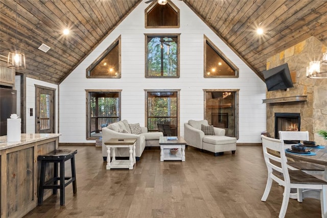 living room featuring dark wood-type flooring, a stone fireplace, high vaulted ceiling, wooden walls, and wood ceiling