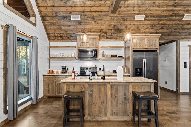 kitchen featuring lofted ceiling with beams, an island with sink, stainless steel appliances, and light stone counters