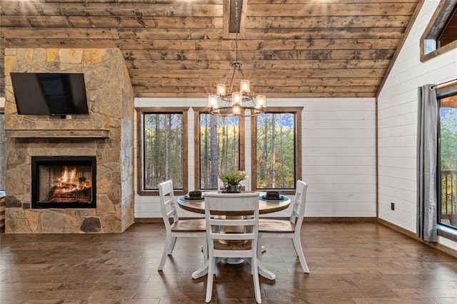 dining area with hardwood / wood-style floors, lofted ceiling, wooden walls, a fireplace, and a chandelier