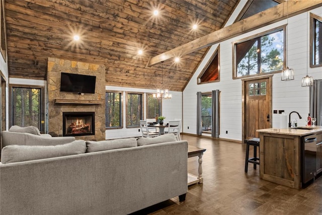 living room with high vaulted ceiling, a stone fireplace, sink, wooden walls, and beam ceiling