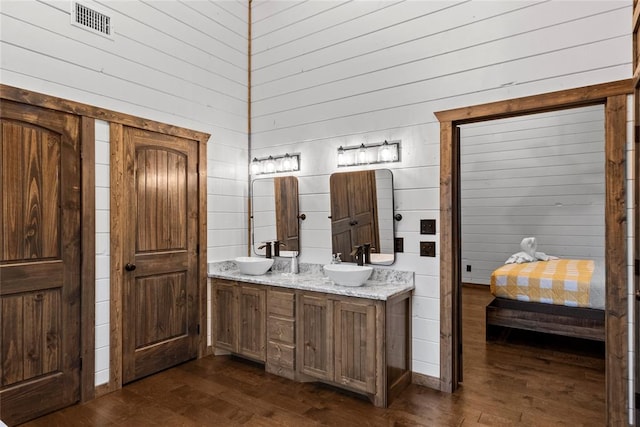 bathroom with wood-type flooring, vanity, and wooden walls