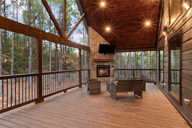 unfurnished sunroom with an outdoor stone fireplace, wooden ceiling, vaulted ceiling, and a healthy amount of sunlight