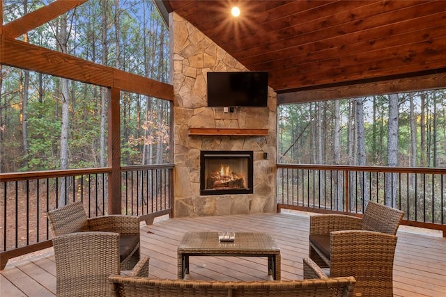 sunroom with lofted ceiling and an outdoor stone fireplace