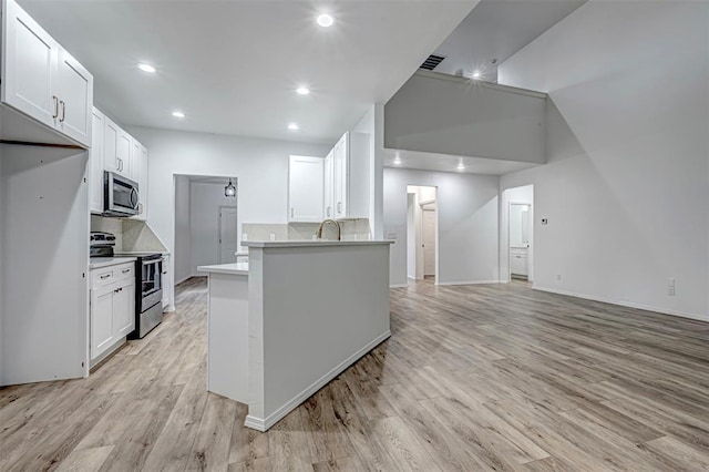 kitchen featuring backsplash, stainless steel appliances, sink, light hardwood / wood-style flooring, and white cabinetry