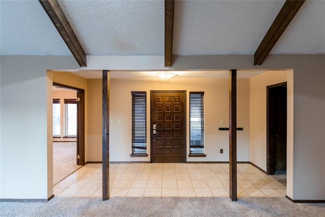 entrance foyer with beamed ceiling, light carpet, and a textured ceiling