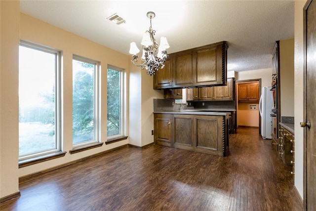 kitchen featuring an inviting chandelier, dark hardwood / wood-style floors, a textured ceiling, decorative light fixtures, and white fridge