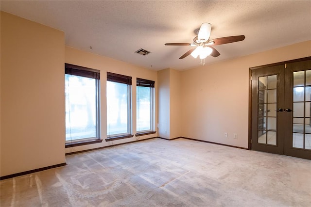 carpeted spare room featuring ceiling fan, a textured ceiling, and french doors