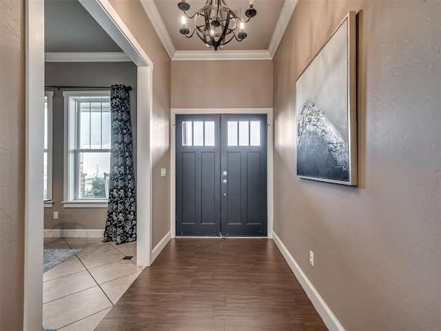 entryway with a chandelier, crown molding, and wood-type flooring