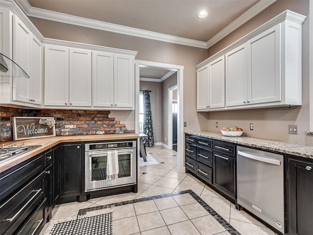 kitchen with crown molding, white cabinets, light tile patterned flooring, and appliances with stainless steel finishes