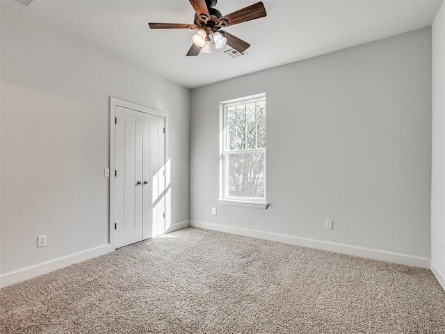 empty room featuring ceiling fan and carpet