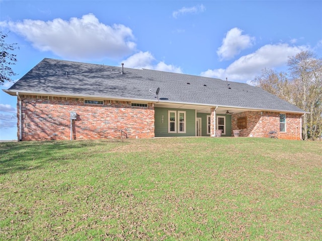 back of property featuring ceiling fan and a yard