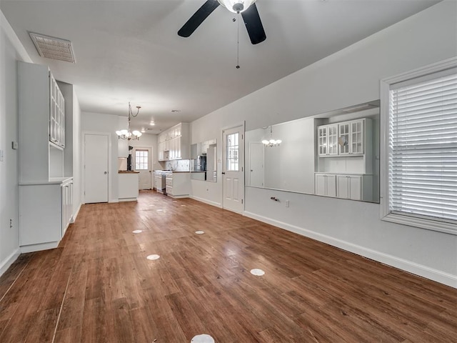 unfurnished living room featuring hardwood / wood-style flooring and ceiling fan with notable chandelier