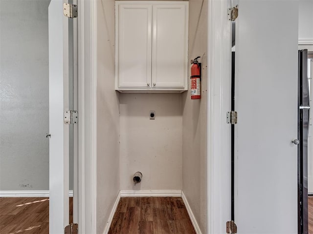 clothes washing area with hookup for an electric dryer, cabinets, and wood-type flooring