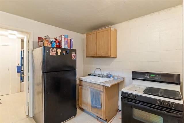 kitchen featuring black refrigerator, sink, and range with gas stovetop