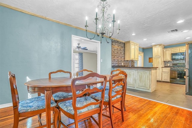 dining room with ceiling fan with notable chandelier, light hardwood / wood-style floors, and crown molding