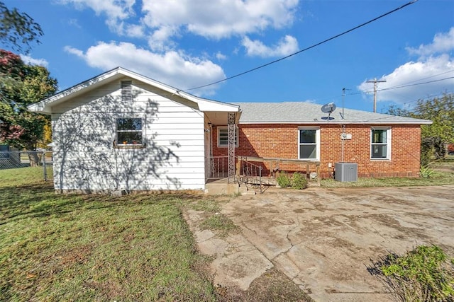 back of house with central AC unit and a lawn